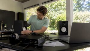 Een muzikant richt zijn thuisstudio in en zet de studiomonitoren op de juiste plek.