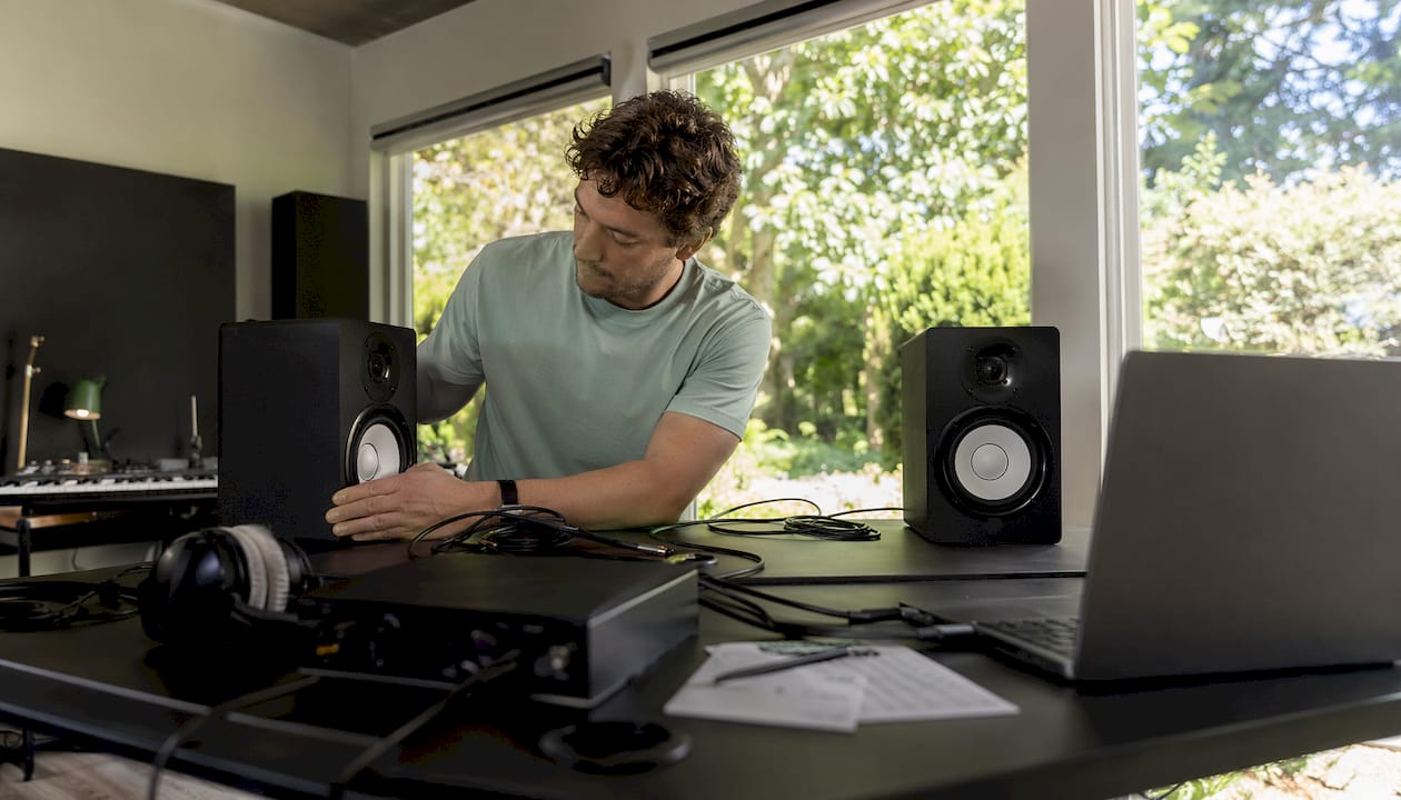 Een muzikant richt zijn thuisstudio in en zet de studiomonitoren op de juiste plek.